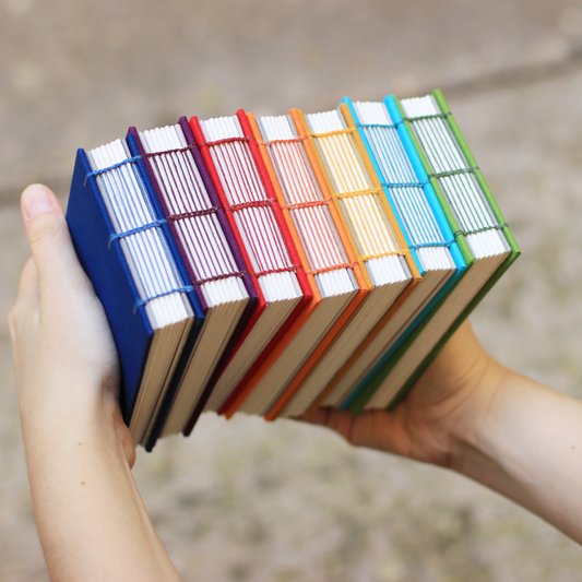 Hand holding a stack of colorful notebooks with a blurred background