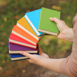 Colorful notebooks held by a person outdoors