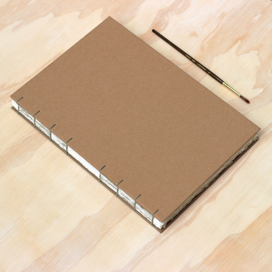 Kraft watercolor arches sketchbook with a paintbrush on a wooden surface