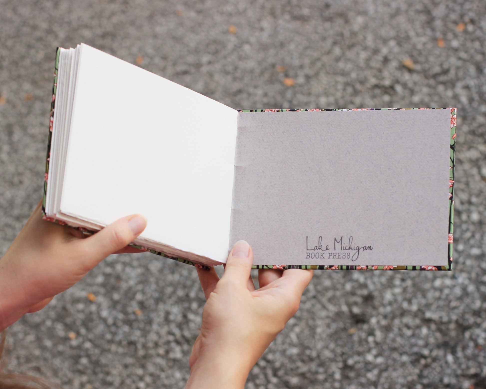 two hands holding open a sketchbook, Lake Michigan Book Press stamped on back interior cover.
