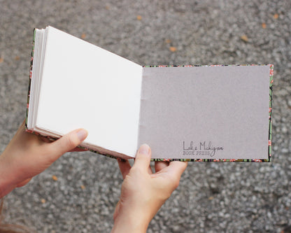 two hands holding open a sketchbook, Lake Michigan Book Press stamped on back interior cover.