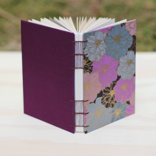 Open sketchbook with floral front cover and purple back cover on a white surface
