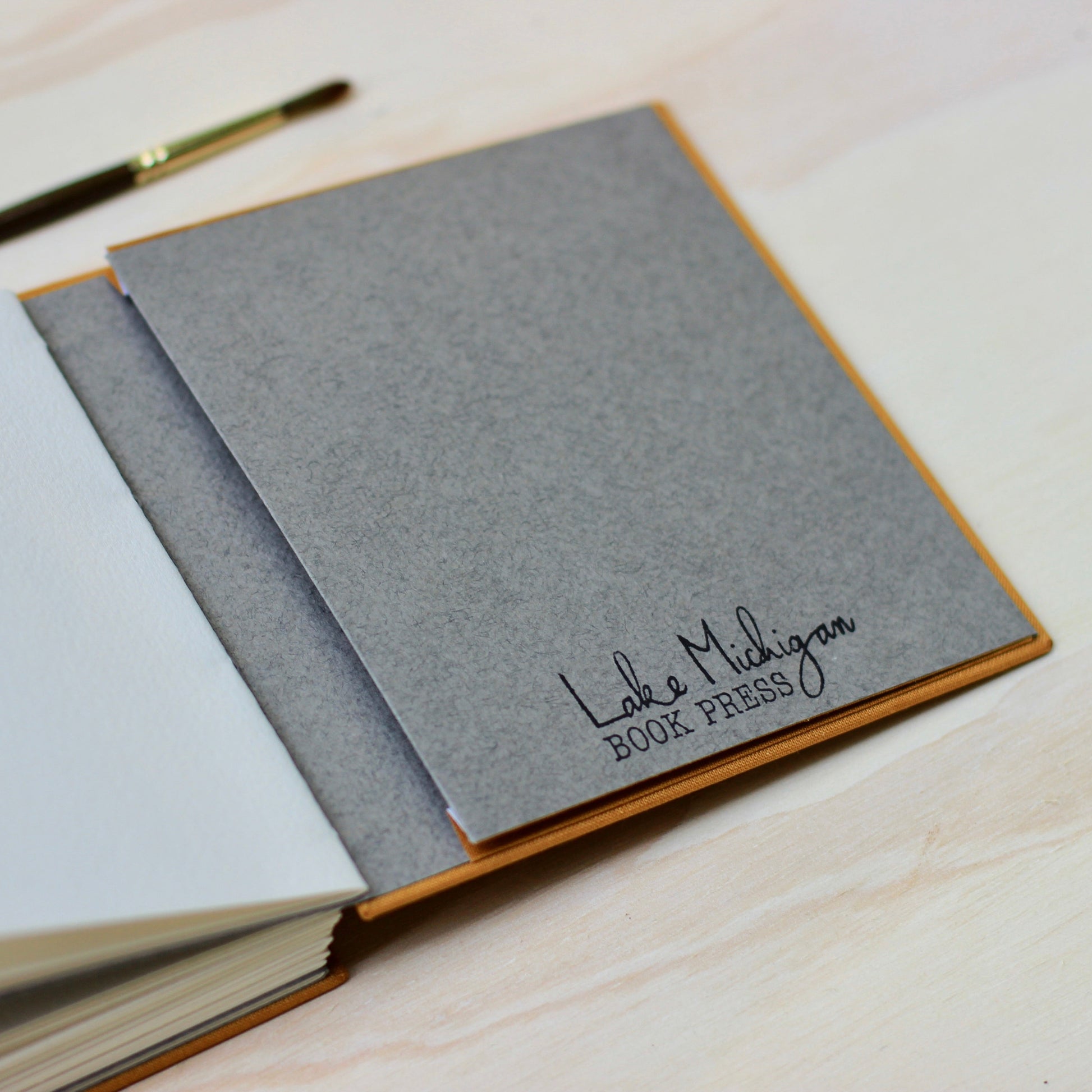 Gray notebook with 'Lake Michigan Book Press' branding on a wooden surface