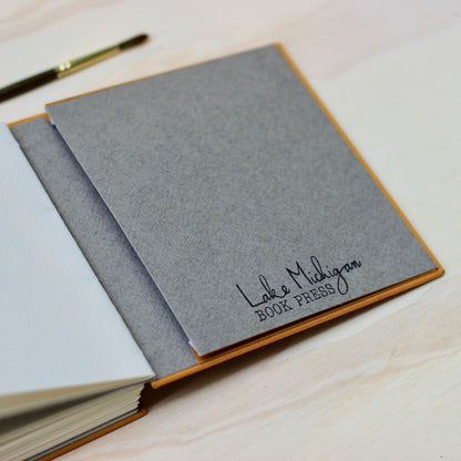 Gray notebook with 'Lake Michigan Book Press' branding on a wooden surface