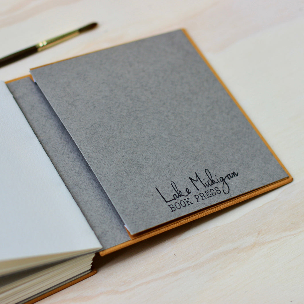 Gray notebook with 'Lake Michigan Book Press' branding on a wooden surface
