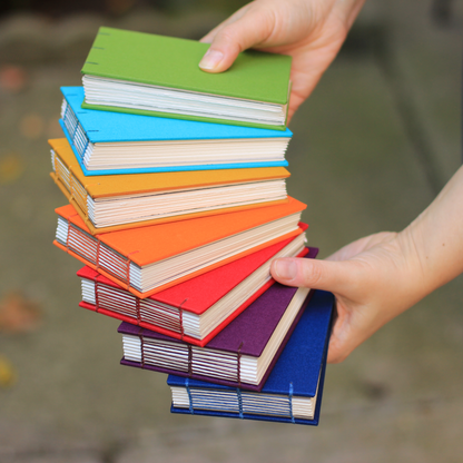 Stack of colorful books held by a person against a blurred background