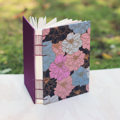 Floral Arches watercolor sketchbook with a purple cover on a wood surface with a nature blurred background