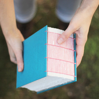 hands holding a turquoise and pink watercolor sketchbook filled with 365 pages